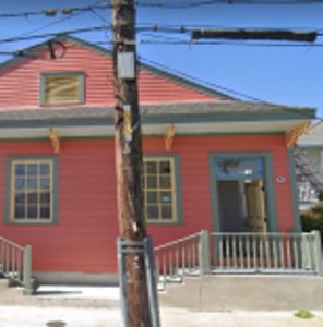 Pink, single story home with blue trim.